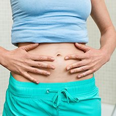 Frau berührt die Haut ihres Bauches